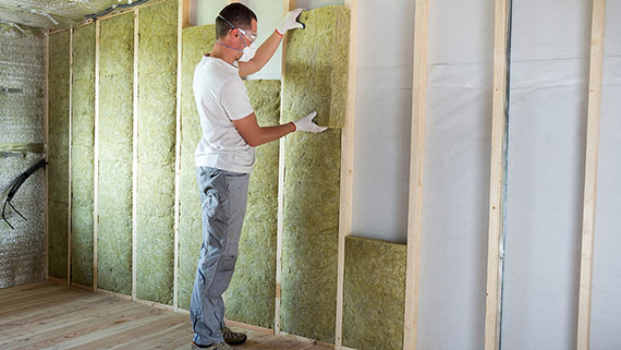 A man on ladder installing insulation
