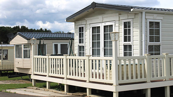 View of the front covered porch of a well maintained mobile with American flag flying