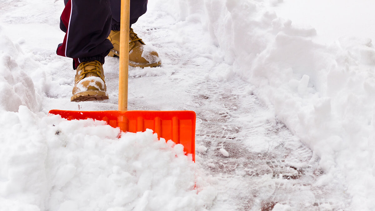 A person shovelling a sidewalk