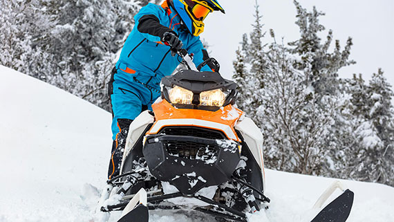 A snowmobiler following a well traveled path through hills