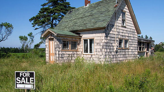 Vacant Home in disrepair and over-grown grass with a for sale sign