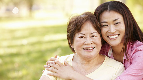 A young woman hugging an elderly woman from behind