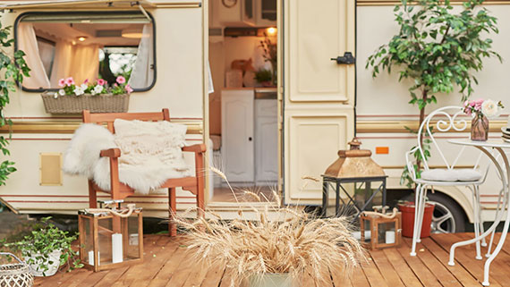 Deck entrance to an rv with custom decor of lanterns, drapes, chairs, and pillows.