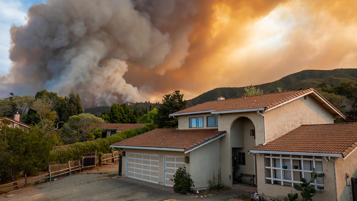 A neighborhood with a looming forest fire in the background